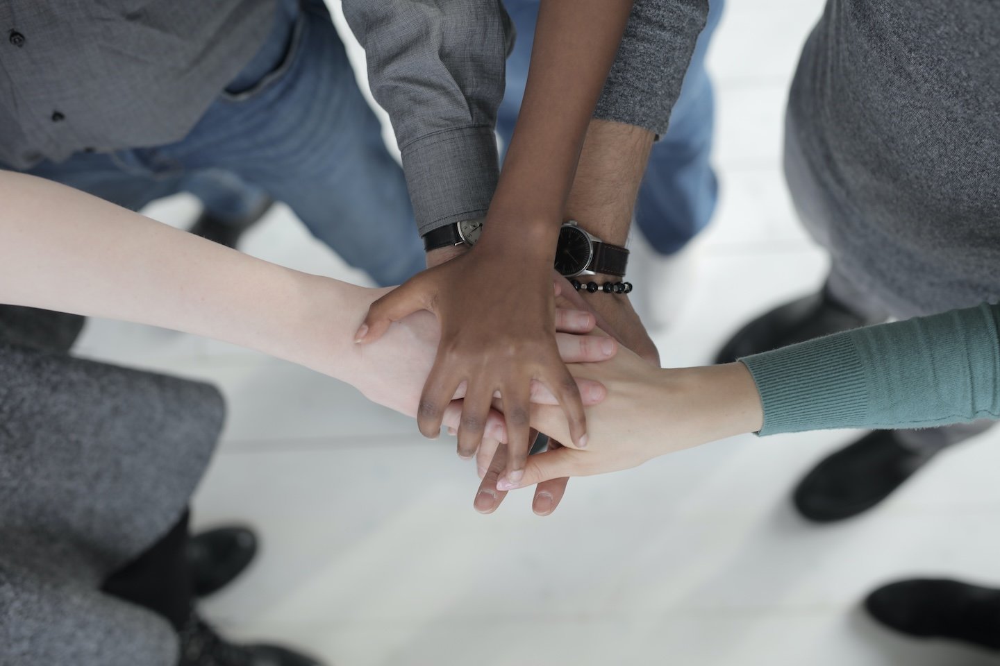 A diverse group of team members placing their hands in the center of a circle.