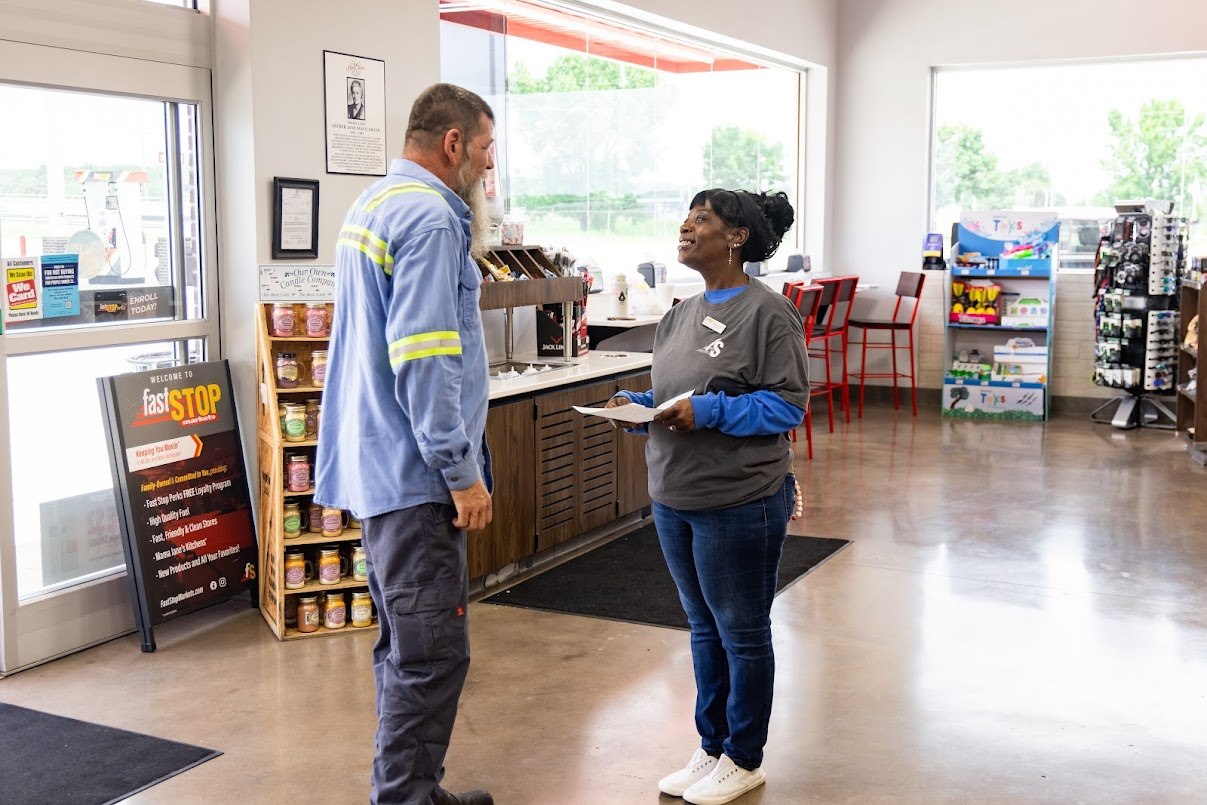 A service attendant talking with a store employee after delivering fuel